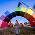 man standing in front of Containbow art installation in fremantle with cherry picker in the background