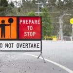 roadworks sign with employee holding slow sign